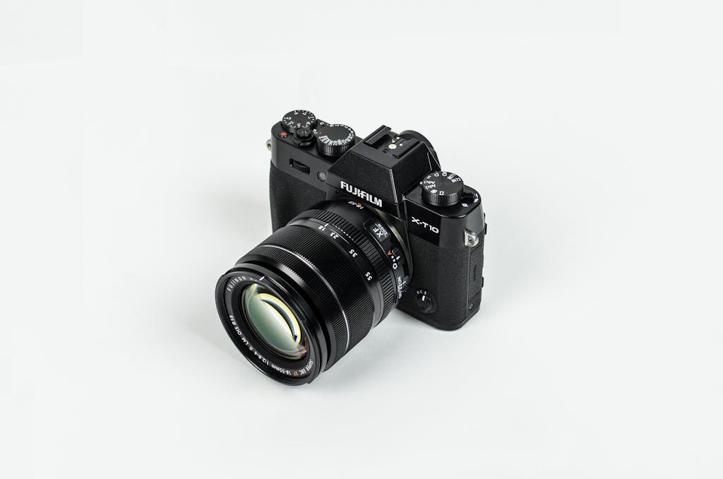 Close-up of a Fujifilm camera with lens on a plain background, showcasing photographic equipment.