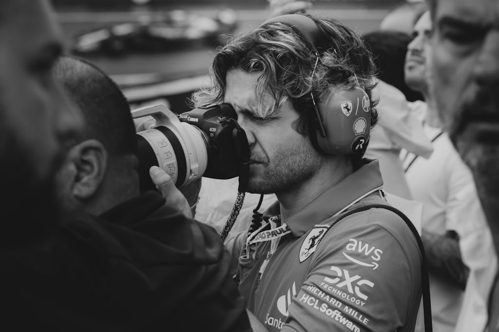 Black and white close-up of a focused photographer capturing a racing scene.